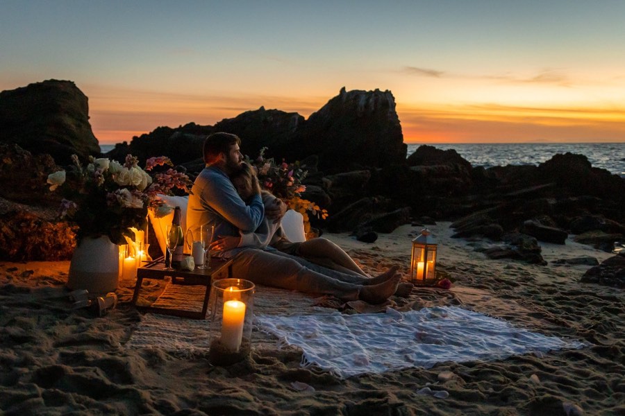 A candlelit picnic set out on the sand at sunset