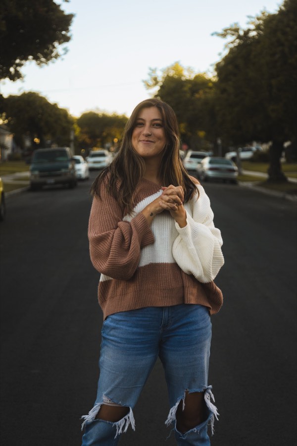 A woman on an empty street holding a cup of coffee