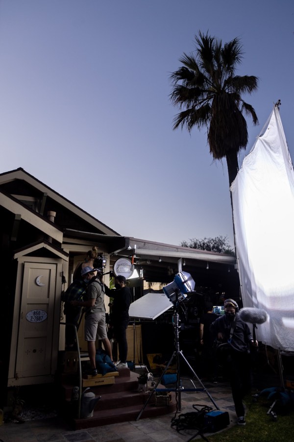 A film set at dusk, lights and diffusion outside a house