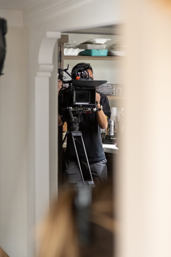 A camera operator framed through an open doorway