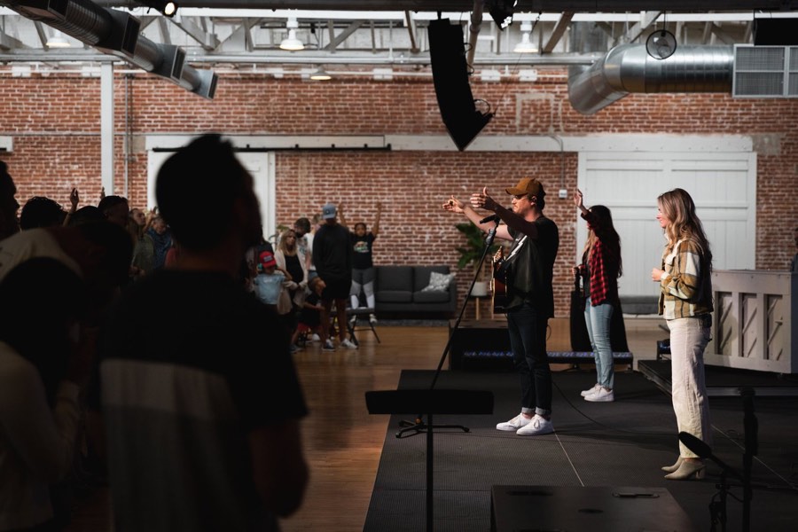 A film crew watching a take in a brick warehouse