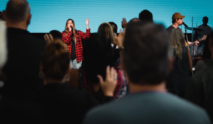 A worship band on stage, hands raised in the crowd