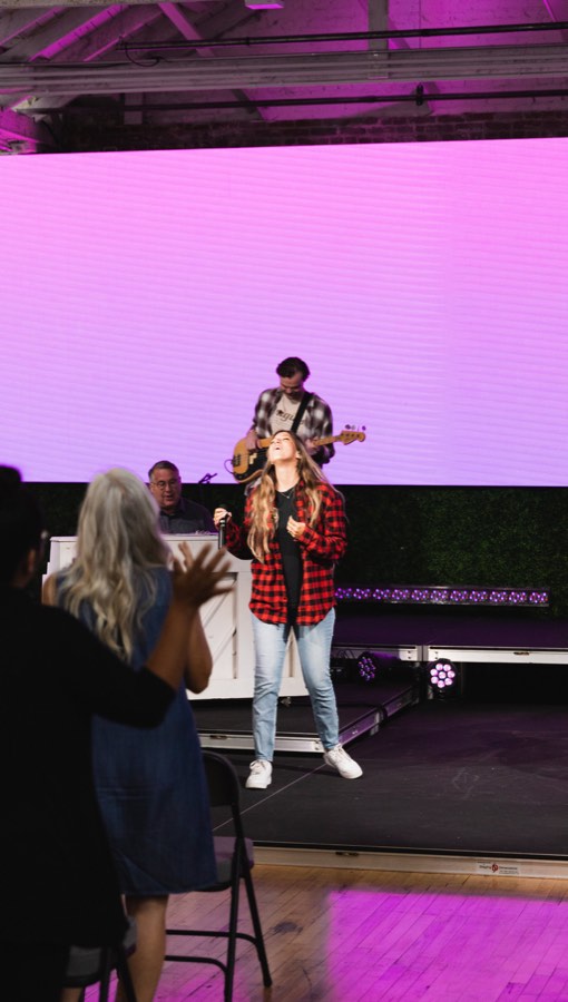 A speaker on a pink-lit stage holding a small child