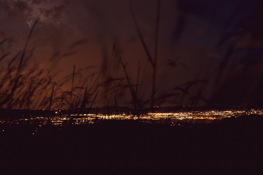 City lights spread out below a dark ridge at dusk