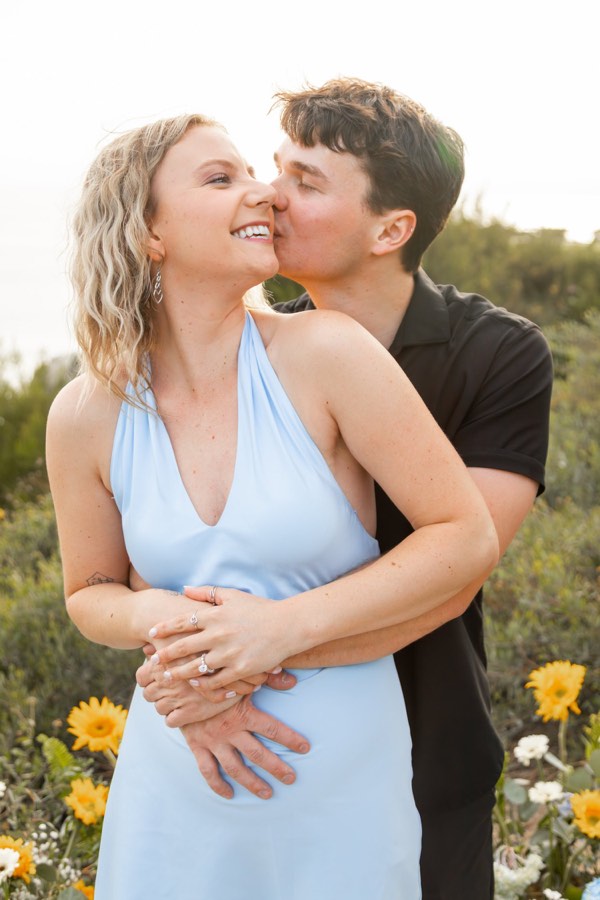 A couple stand together in a field of yellow wildflowers