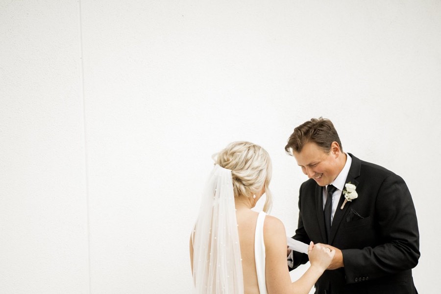 A groom reads his vows aloud to his bride