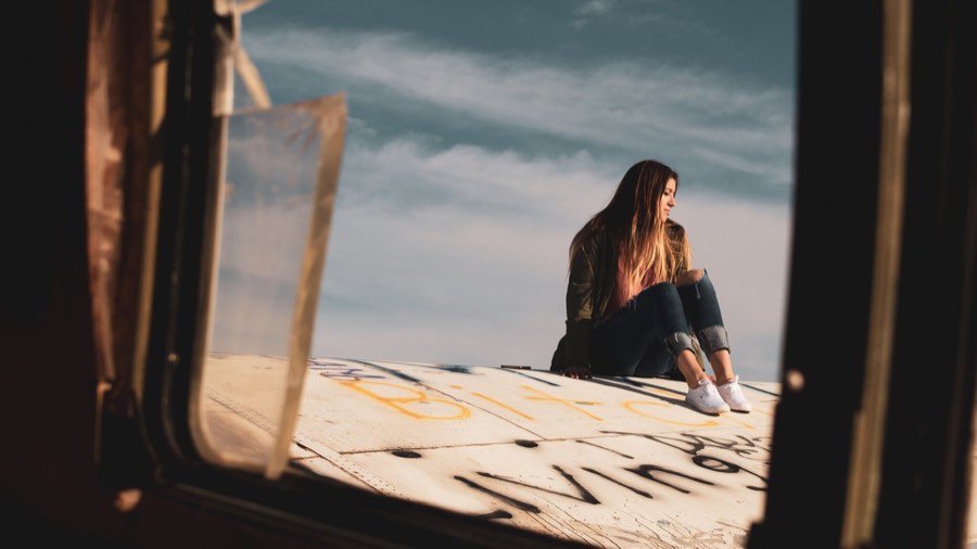A woman sits in an open van doorway with the ocean behind her