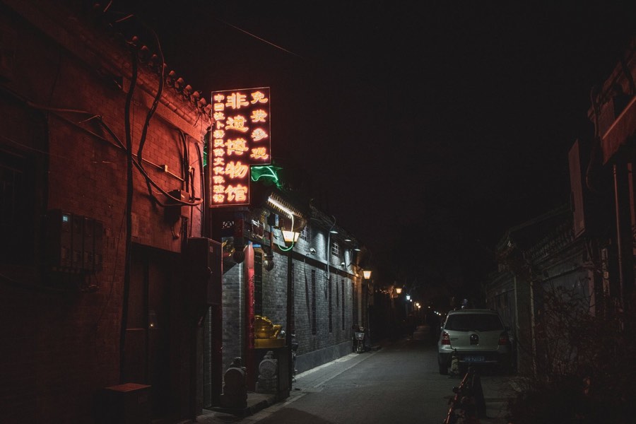 Red neon signs down an empty alley at night