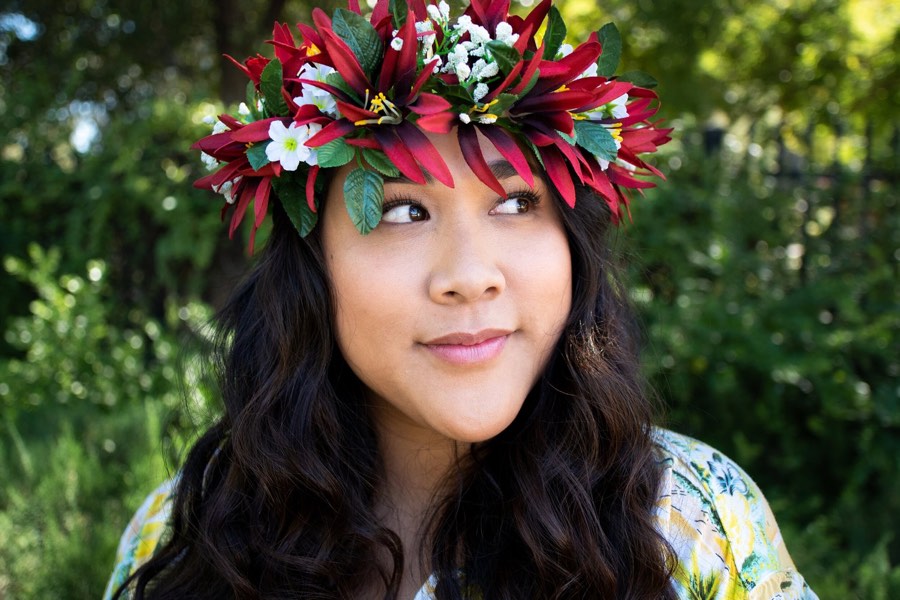 A woman wearing a red and green flower crown in the shade