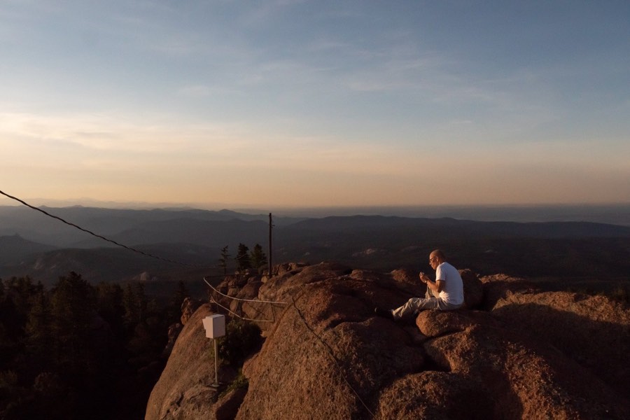 A lone figure sitting on a granite outcrop at dusk