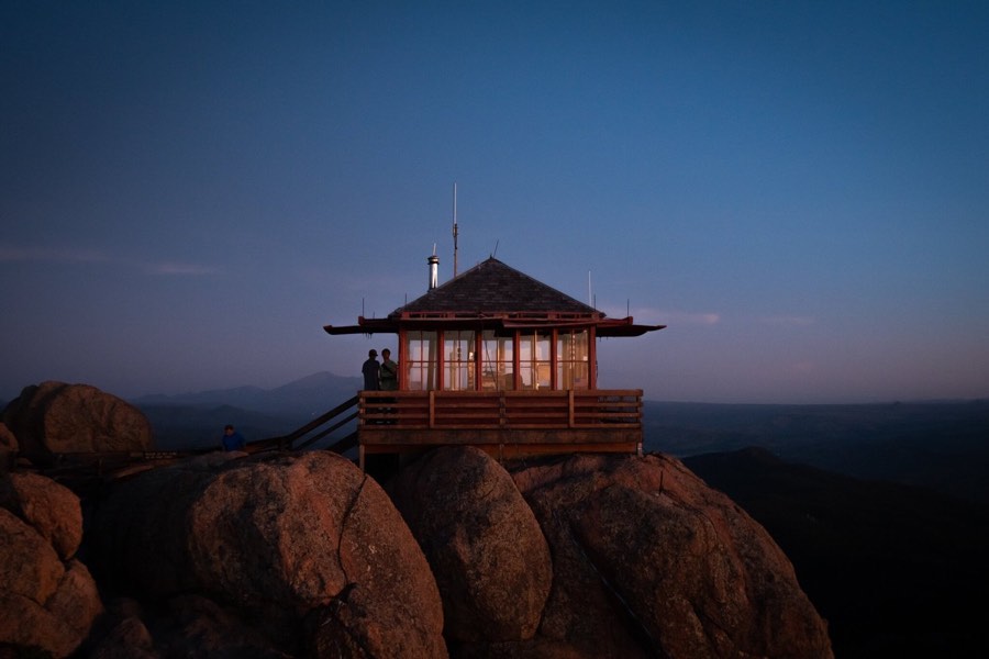 A fire lookout tower perched on granite boulders at dusk