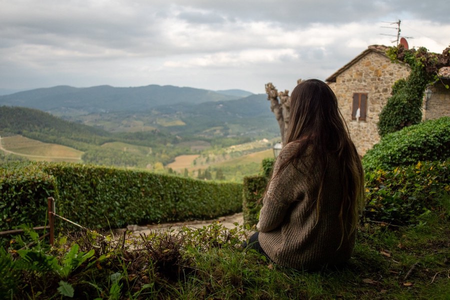 A woman looks out over the Tuscan hills from a stone wall