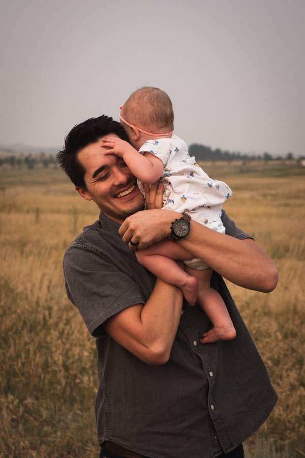 A man holding his baby close in a golden field